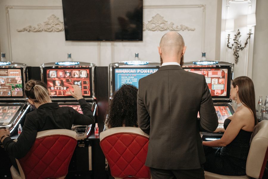 Beberapa pemain dewasa mencoba mesin slot di lantai kasino